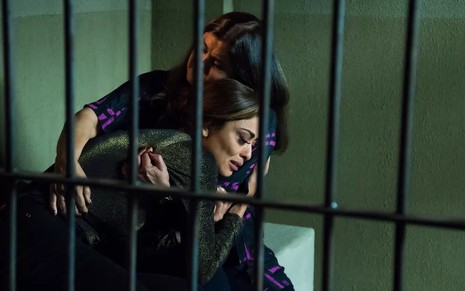 A atriz Juliana Paes, atrás das grades, no colo da atriz Elizangela em cena de A Força do Querer