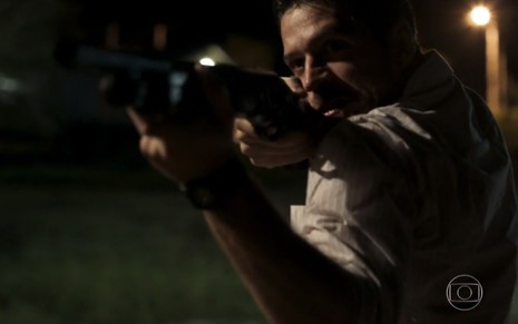 O ator Marco Pigossi com uma espingarda na mão, em cena como Zeca na novela A Força do Querer