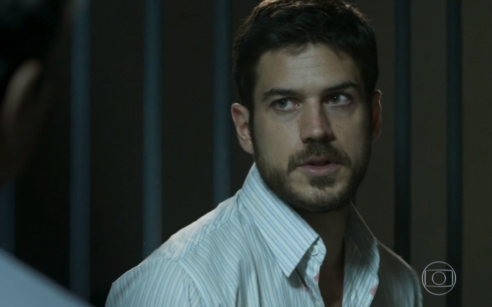 O ator Marco Pigossi em uma cela, usando uma camisa branca, como Zeca em A Força do Querer