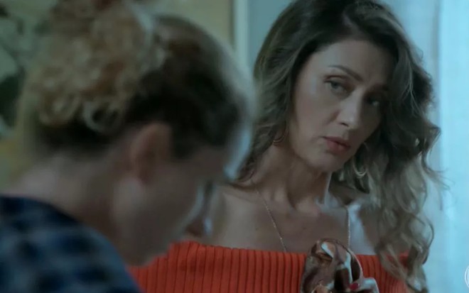 A atriz Maria Fernanda Cândido, com uma blusa vermelha e expressão de desagrado, em cena como Joyce em A Força do Querer