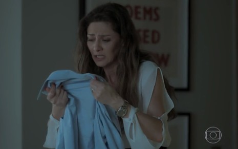 A atriz Maria Fernanda Cândido, segurando uma camisa e chorando, em cena como Joyce em A Força do Querer