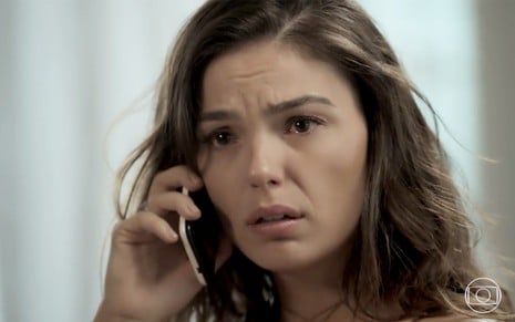 Isis Valverde em cena de A Força do Querer: personagem atende o celular e olha com desespero para o horizonte