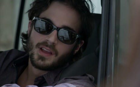 Fiuk em cena de A Força do Querer: caracterizado como Ruy, personagem está dentro do carro de óculos escuros e olha com deboche para alguém fora do quadro