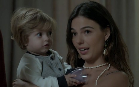 Lorenzo Souza e Isis Valverde em cena de A Força do Querer: a criança no colo, atriz olha com indagação para alguém fora do quadro