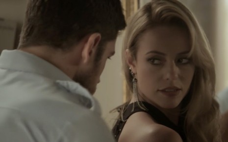 Marco Pigossi e Paolla Oliveira em cena de A Força do Querer: de costas, ator ajeita o vestido da atriz que o olha de maneira sedutora