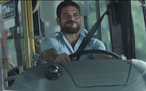 O ator Marco Pigossi, dirigindo um ônibus, em cena como Zeca em A Força do Querer