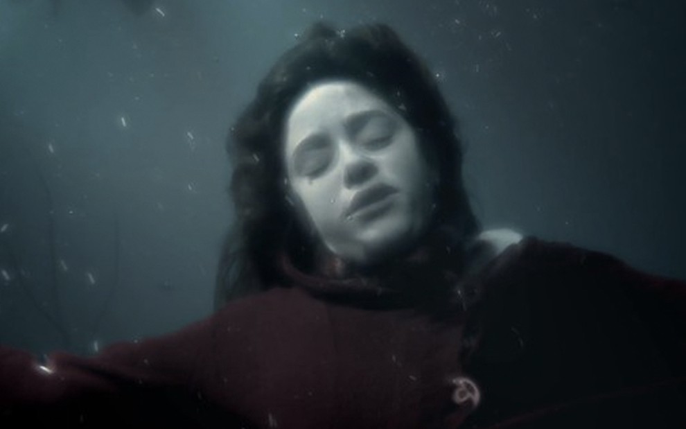 A atriz Fernanda Vasconcellos, como Ana, parece se afogar dentro de um lago com águas turvas e azuladas em cena de A Vida da Gente
