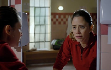 A atriz Fernanda Vasconcellos como Ana se olha no espelho, ela tem expressão de tristeza e lágrimas nos olhos, em cena de A Vida da Gente