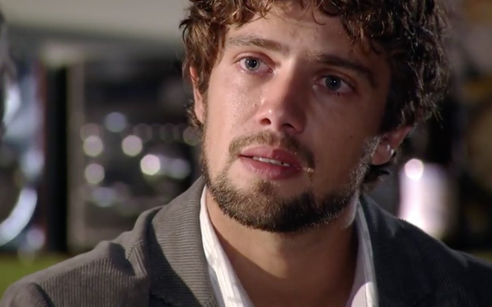 O ator Rafael Cardoso com expressão de tristeza como Rodrigo em um ambiente fechado, que parece ser uma sala de estar, em cena de A Vida da Gente