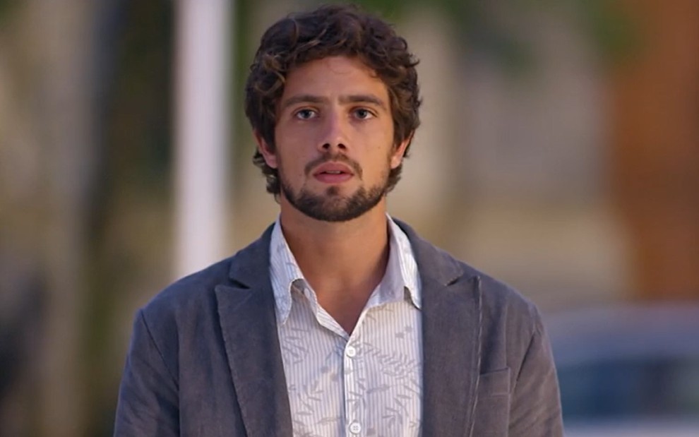 Rafael Cardoso grava de camisa branca e blazer cinza com cara séria e desolada como Rodrigo