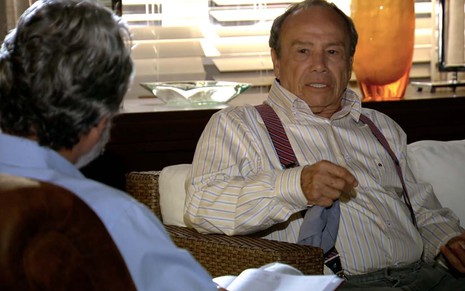 O ator Stênio Garcia está sentado em um sofá, com expressão de preocupação, como o Laudelino em cena de A Vida da Gente