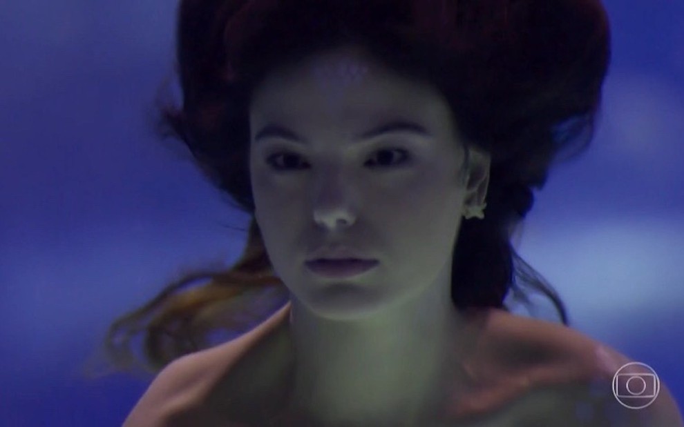 A atriz Isis Valverde grava cena nadando dentro de um tanque com peixes, usando uma causa de sereia, em A Força do Querer