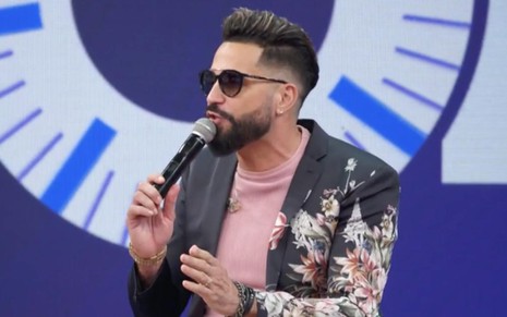 O cantor Latino de óculos escuros, camiseta rosa e terno preto estampado no estúdio do Altas Horas
