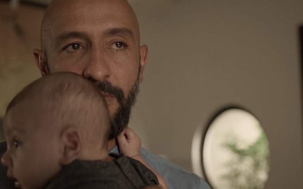 O ator Irandhir Santos segura o bebê que que interpreta o filho de seu personagem na novela Amor de Mãe, da TV Globo
