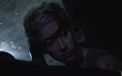 A atriz Camila Márdila, com sangue no rosto, encena a morte de sua personagem, Amanda, em acidente de carro em Amor de Mãe