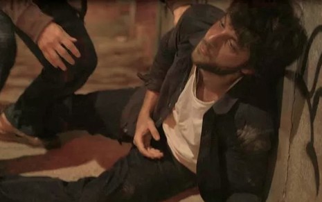 O ator Chay Suede caído na rua caracterizado como o Danilo em cena de Amor de Mãe