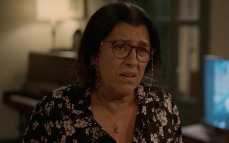 Regina Casé em cena de Amor de Mãe: caracterizada como Lurdes, personagem faz cara de confusão para alguém fora do quadro