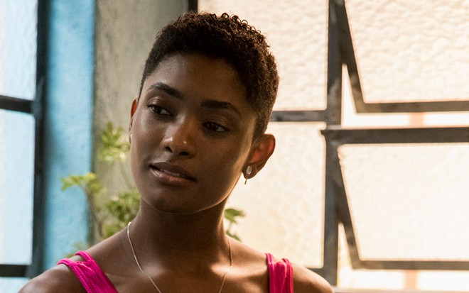 A atriz Erika Januza, com um top rosa, caracterizada como a Marina em cena de Amor de Mãe, da TV Globo