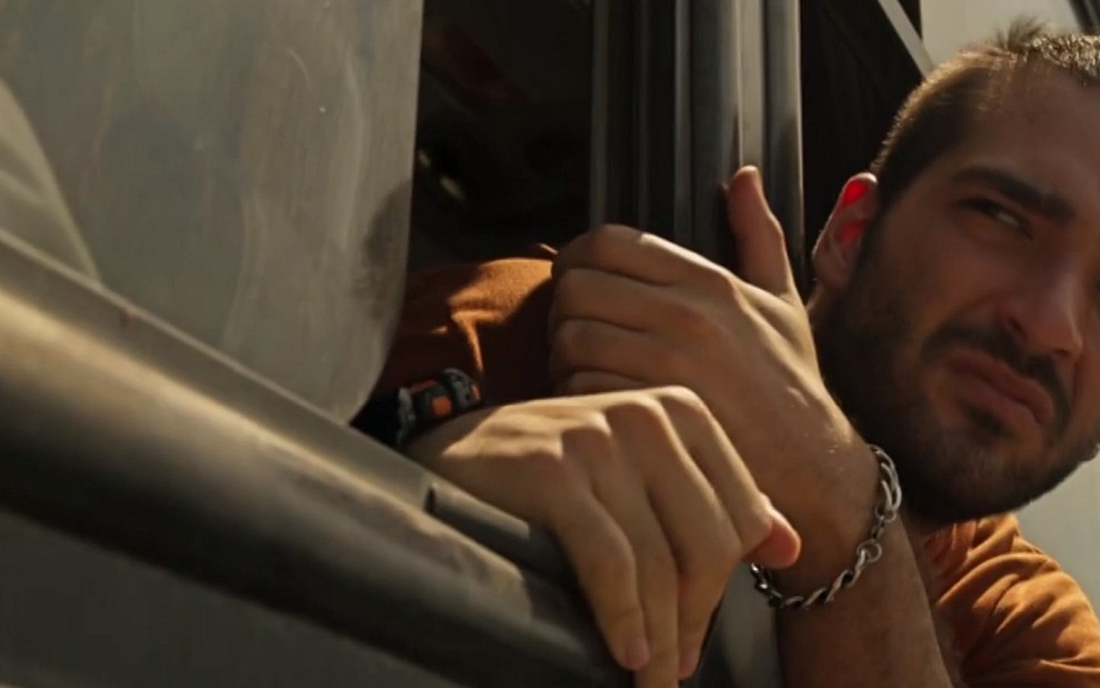 Sandro (Humberto Carrão) com a cabeça para fora do ônibus em cena de Amor de Mãe