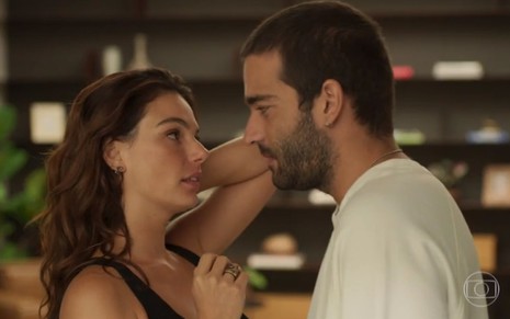 Os atores Isis Valverde e Humberto Carrão, de frente um para o outro, prestes a trocarem um beijo, em cena como Betina e Sandro em Amor de Mãe