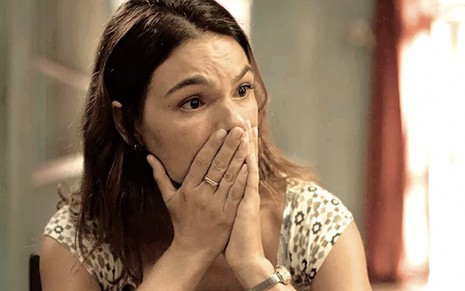 Em um close em seu rosto, a atriz Isis Valverde leva as mãos a boca, em sinal de surpresa, caracterizada como a Betina em cena de Amor de Mãe