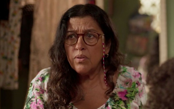 Regina Casé em cena de Amor de Mãe: caracterizada como Lurdes, personagem faz cara de confusão para alguém fora do quadro