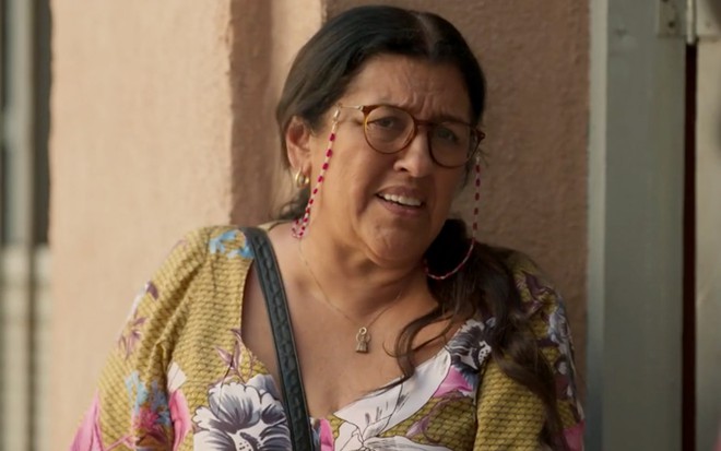 Regina Casé em cena de Amor de Mãe: caracterizada como Lurdes, personagem faz cara de confusão para alguém fora do quadro