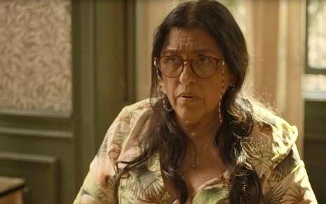 A atriz Regina Casé usa uma blusa estampada e óculos em cena da novela Amor de Mãe, da TV Globo