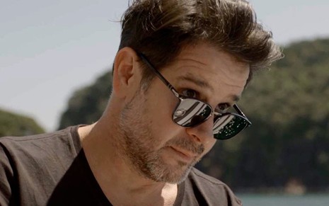 O ator Murilo Benício arregala os olhos por cima dos óculos escuros em cena da novela Amor de Mãe, da TV Globo