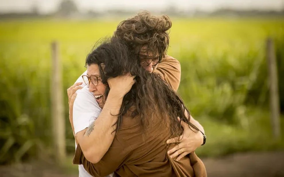 Chay Suede e Regina Casé em cena de Amor de Mãe: personagens estão no campo e se abraçam