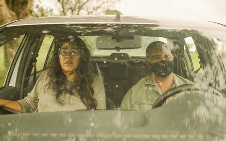 Dentro de um carro, Regina Casé como Lurdes tem expressão sofrida enquanto Eduardo BR, o Veiga, segura o volante em cena de Amor de Mãe