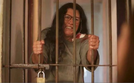 A atriz Regina Casé, trancada em uma jaula, em cena como Lurdes em Amor de Mãe