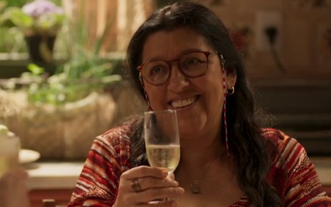 Lurdes (Regina Casé) brinda com champanhe em cena de Bom Sucesso
