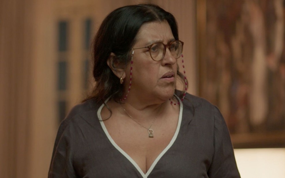 A personagem Lurdes (Regina Casé) olha surpresa em cena da novela Amor de Mãe, da Globo