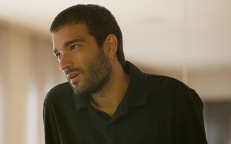 Humberto Carrão caracterizado como Sandro em Amor de Mãe: personagem olha seriamente para alguém fora do quadro