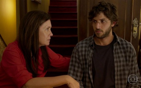 Adriana Esteves e Chay Suede em cena de Amor de Mãe: sentados, atriz olha com preocupação para o rapaz e ele retribuiu com uma feição de desconfiança