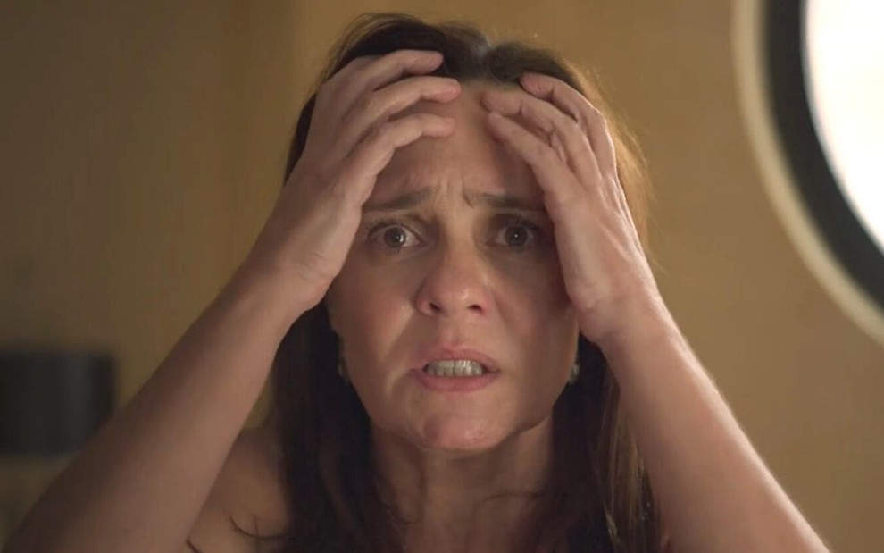 A atriz Adriana Esteves leva as mãos à cabeça em desespero como Thelma em cena de Amor de Mãe