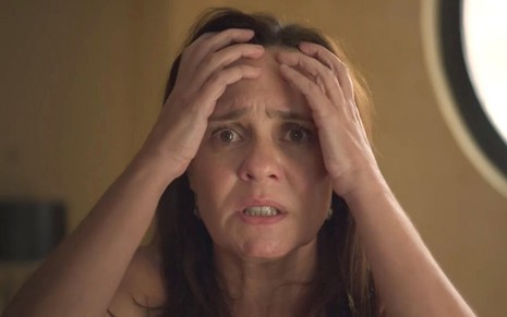 A atriz Adriana Esteves leva as mãos à cabeça em desespero como Thelma em cena de Amor de Mãe