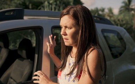 A atriz Adriana Esteves se apoia em carro em cena de Amor de Mãe, novela na qual interpreta a vilã Thelma