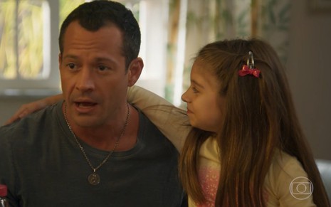 O ator Malvino Salvador com uma criança no colo em cena da novela das sete Haja Coração