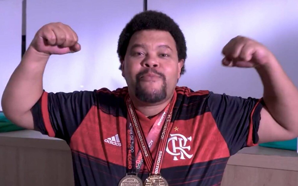 Com camisa do Flamengo e medalhas penduradas no pescoço, Babu faz sinal de força e olha para câmera