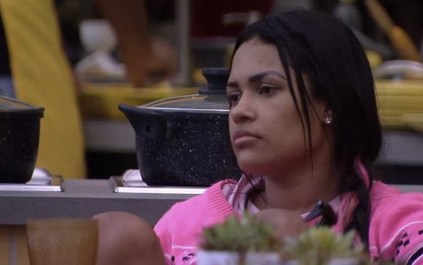 A sister Flayslane sentada em uma mesa na área externa da casa do Big Brother Brasil 20
