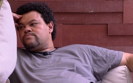 O ator Babu Santana sentado no sofá, com expressão triste, durante o BBB20