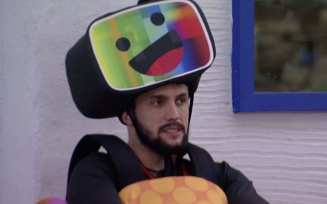 O participante Arthur Picoli vestido com um chapéu de TV sorridente no BBB21