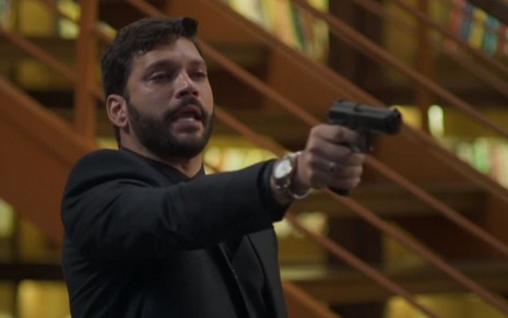 O ator Armando Babaioff com uma arma na mão, em cena como o personagem Diogo em Bom Sucesso
