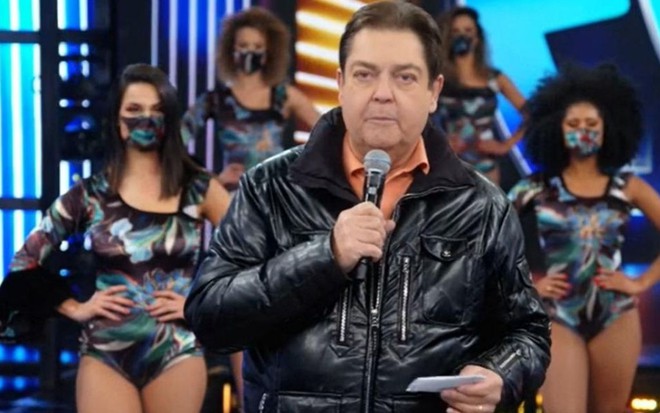 Fausto Silva durante o Domingão do Faustão deste domingo (23); ao fundo as bailarinas usam máscara