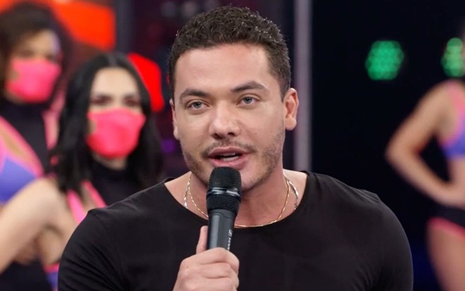 Wesley Safadão falando no palco do Domingão do Faustão, da Globo, com bailarinas ao fundo