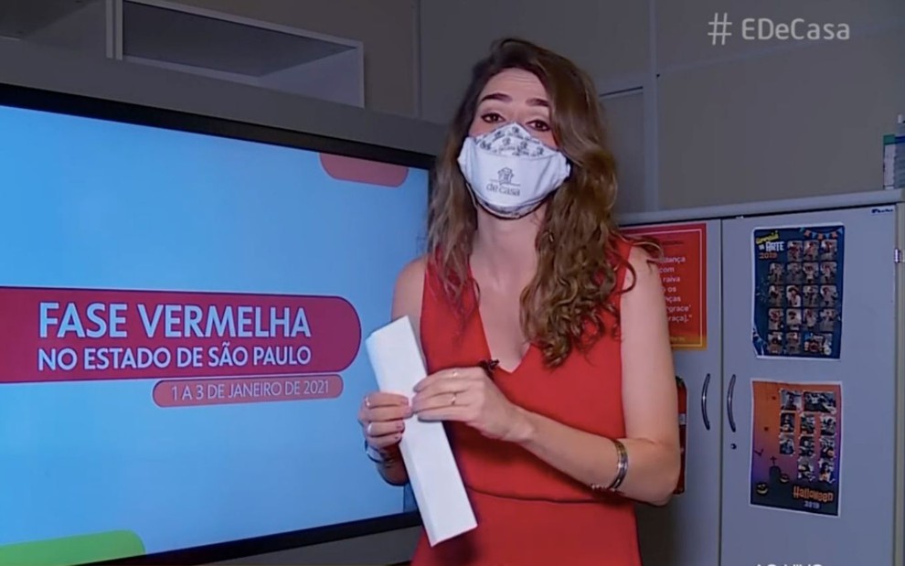 A repórter Gabriela Liam de máscara e com papel na mão, de roupa vermelha, durante participação no É de Casa