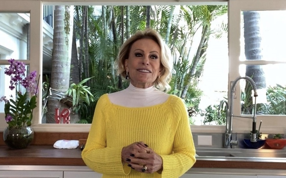 A apresentadora Ana Maria Braga em uma cozinha com um pulôver amarelo