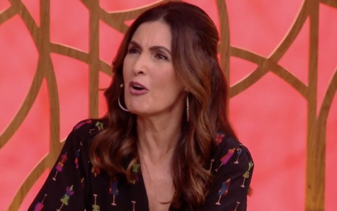 Com cabelo ultrapassando os ombros e de macacão preto com detalhes colorido, Fátima Bernardes faz cara de espanto no Encontro